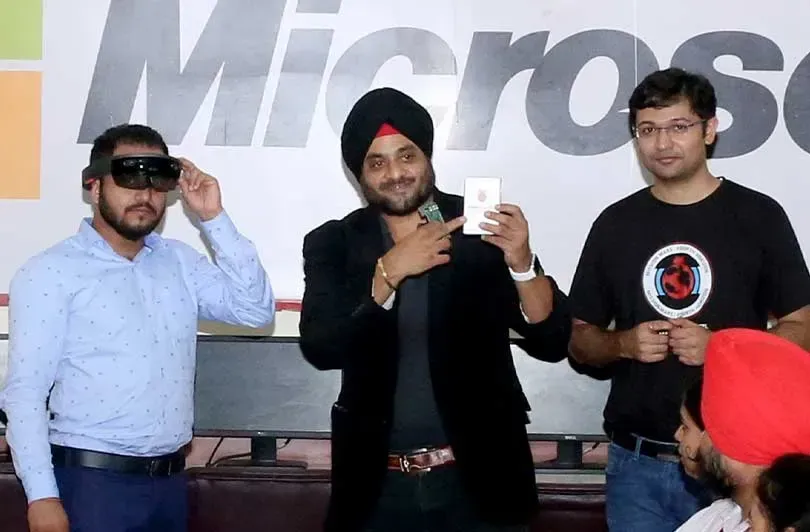 Students trying on mixed-reality headsets in front of a Microsoft backdrop