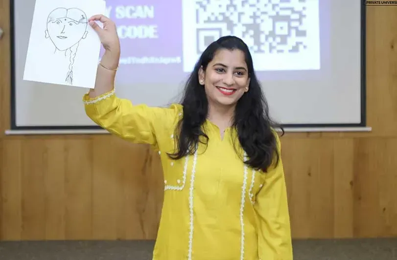 A woman holding up a sketch during a session in front of a projected screen